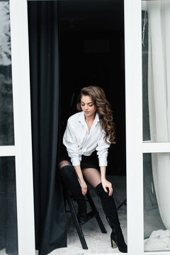 Stylish woman in thigh high boots posing on a stool