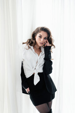 Beautiful young woman posing confidently by white curtains