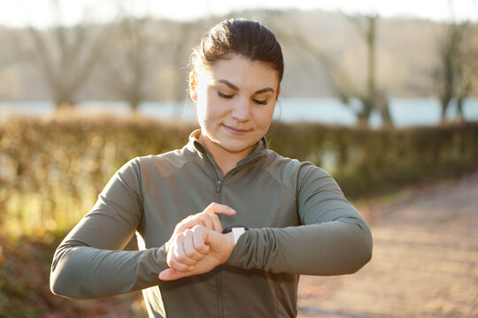 Young athletic woman looks at training success on her smartwatch after exercise on a sunny winter morning	