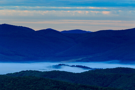 Misty Carpathian mountains at sunrise. Fog drifting through mountain valleys