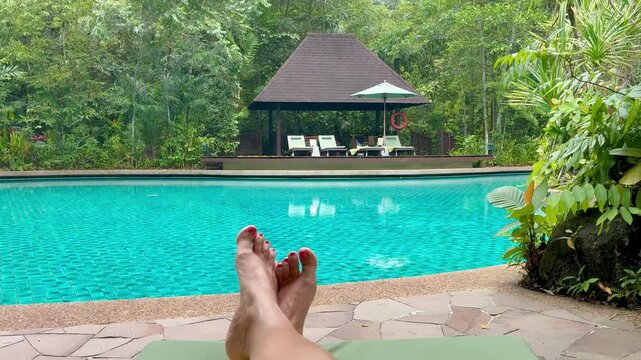 Womans beare feet against the swimming pool in the luxury torpical resort
