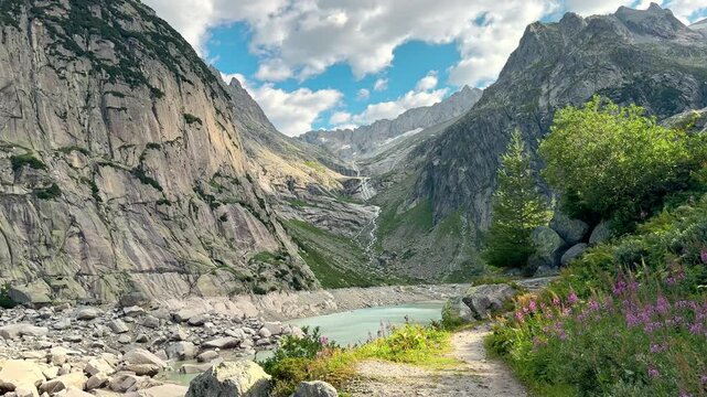 Wildflowers border a path above turquoise Gelmersee in Switzerland outdoors, Rocky Alpine basin and dramatic peaks frame a peaceful mountain lake outdoors
