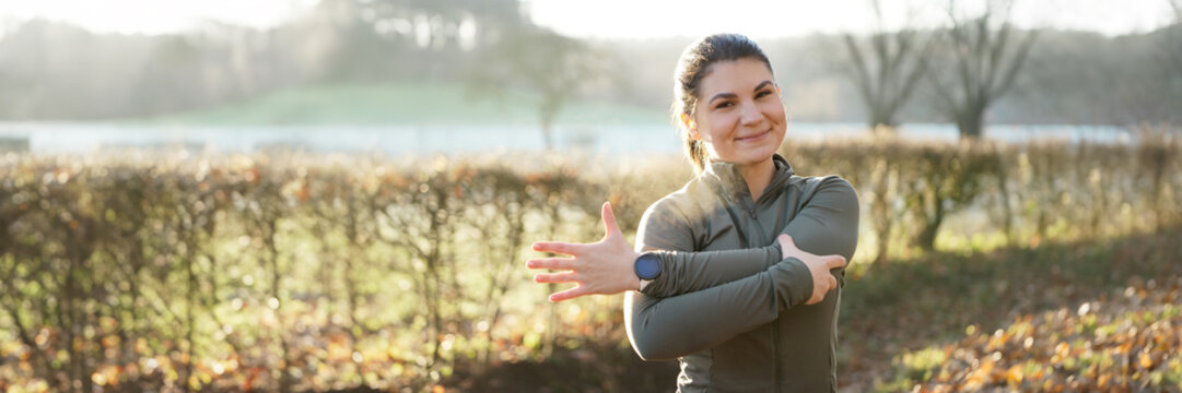 Athletic young woman is stretching after workout, training and running on a beautiful winter morning, panoramic view	

