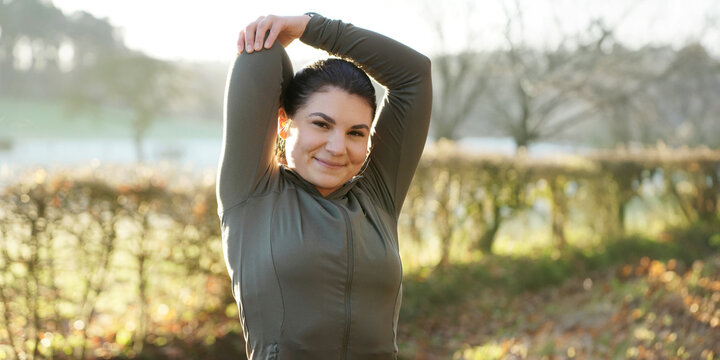 Athletic woman is doing stretching exercises after workout, training and running on a beautiful winter morning, panoramic view
