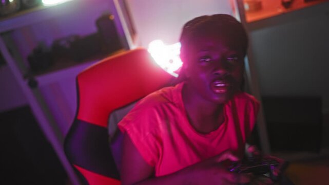 Woman holding game controller with both hands, fingers on buttons, leaning forward in red gaming chair under neon lights in a studio; victory excitement.
