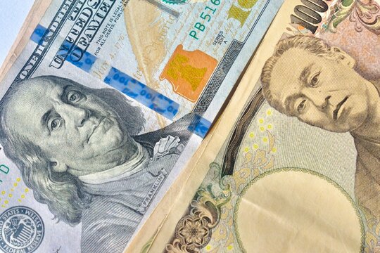 Close-up of a Benjamin Franklin 100 US dollar bill aligned with a Japanese 10000 yen banknote, illustrating bilateral trade, foreign exchange, and currency strength.