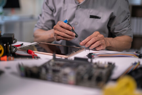 Engineer repairing tablet electronics with small screwdriver