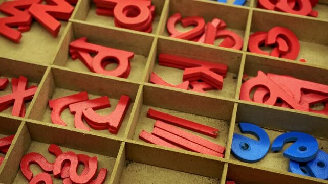A wooden organizer drawer filled with small colorful alphabet letters used for educational games and children learning literacy in a classroom setting during a creative school activity session