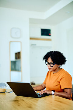 Woman focusing on her work, typing on a laptop keyboard. Remote worker in a modern home environment, staying productive