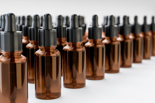 Amber glass dropper bottles filled with cosmetic or Aromatherapy liquid, arranged in rows white background. Skincare, serum, laboratory and beauty oil product concept.