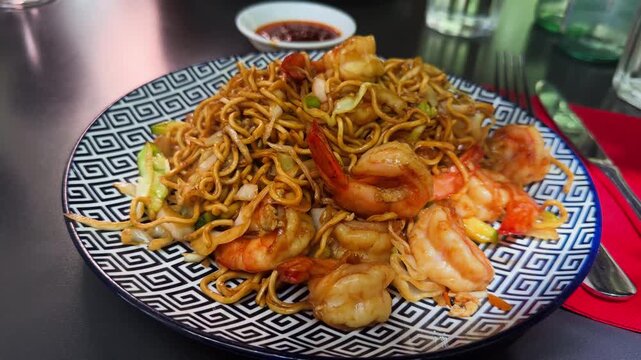 Plate of yakisoba noodles with shrimp on decorative dish, Asian stir-fried noodle dish served in restaurant. High quality 4k footage