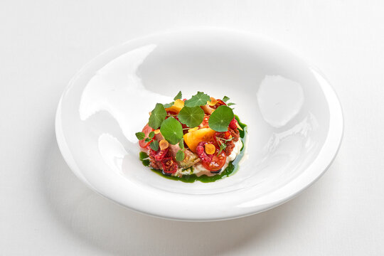 Gourmet salad with fresh tomatoes, stracciatella cheese, and herbs isolated on white background.