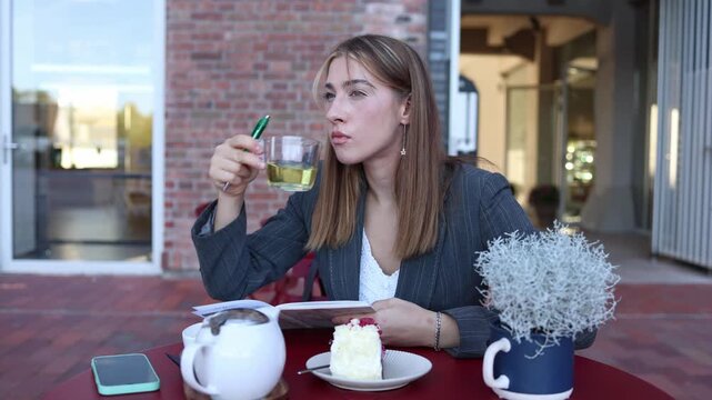 Food critic tastes tea at an outdoor cafe and reacts with clear disgust while taking notes about poor flavor drink quality and disappointing cafe services