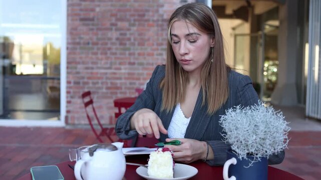 Food critic carefully examines a bite of cake while taking notes at an outdoor cafe evaluating dessert quality taste presentation and customer experiences