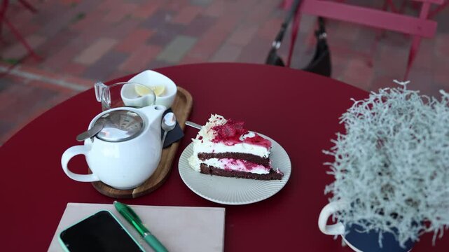 An untouched slice of cake and cooling tea remain on an empty cafe table suggesting someone stepped away suddenly leaving their quiet afternoon break unfinished for today