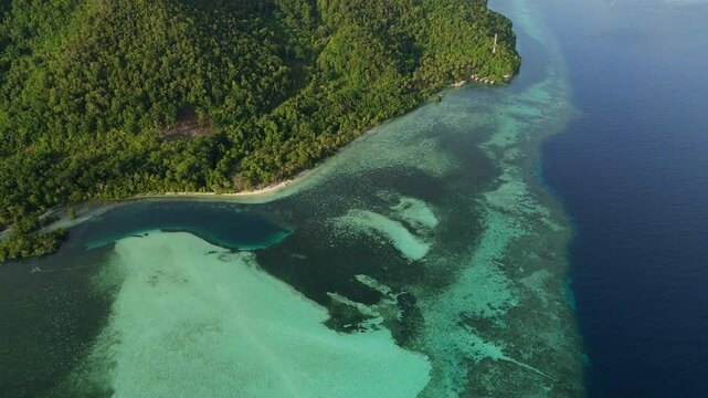 Cinematic aerial view of Mansuar Island in Raja Ampat Indonesia at golden hour sunset &ndash; Breathtaking drone shot of tropical palm beach, vibrant coral reef and glowing turquoise ocean water 4k UHD