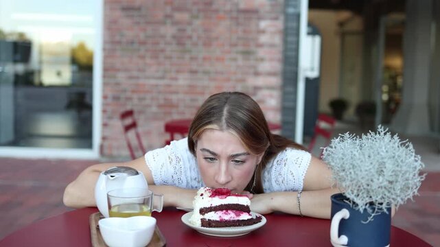 Woman waits for her scheduled eating time at a cafe while staring at cake following a strict meal timing routine and resisting food until the selected daily eating window