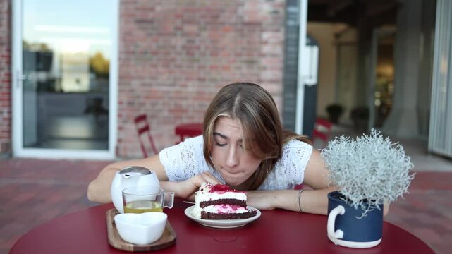 Woman hesitates over a tempting berry cake at an outdoor cafe staring at dessert and wondering whether she should eat it while struggling with temptation and self control