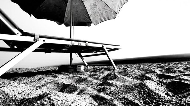 Black and White Peaceful Beach Scene with Lounging Chair and Umbrella on Sand with Tranquil Calm Atmosphere