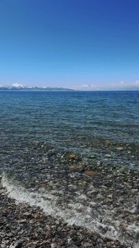 Beautiful scenic view of Sayram Lake with turquoise water and snow-capped Tianshan mountains in Xinjiang, China.