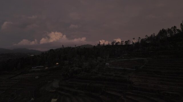 Aerial drone view of terrace garlic farms and stepped agricultural fields in Poondi, nestled in the Palani Hills of the Western Ghats, Tamil Nadu, glowing at twilight beneath colorful clouds.