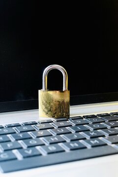 Metallic padlock placed on a laptop keyboard, symbolizing computer security, data protection, and cybersecurity compliance.