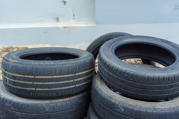 Pile of used car tires against urban wall © IbragimovN