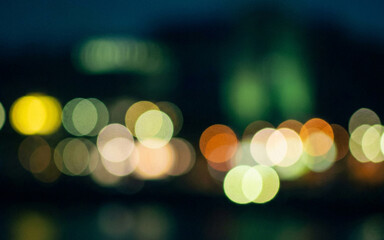 Fototapeta premium A beautiful blurred night scene featuring colorful bokeh lights reflecting off water, creating a dreamy, atmospheric effect perfect for backgrounds and graphic design.