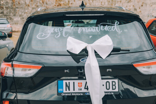 July 12, 2026, Nis, Serbia: Ford Kuga rear view decorated with white bow and just married sign. Wedding car detail.