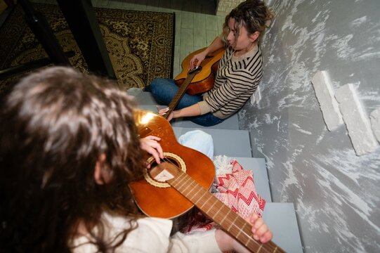 Musical moments shared between friends filled with laughter and harmony during a cozy gathering on the stairway in a charming home setting at night