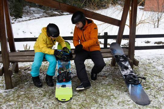 Exciting moments of winter sports preparation in a snowy landscape with a mentor guiding a young snowboarder on a crisp day in the mountains