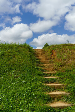 Stone steps leading up grassy hill under blue sky