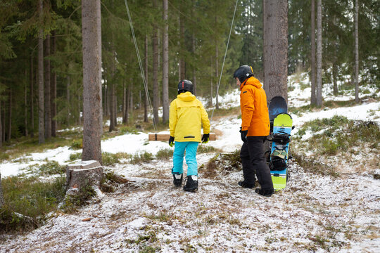 Winter fun takes shape as two adventurers prepare for an exciting day of snowboarding in a serene forest, surrounded by snowy pines on a chilly morning in the mountains