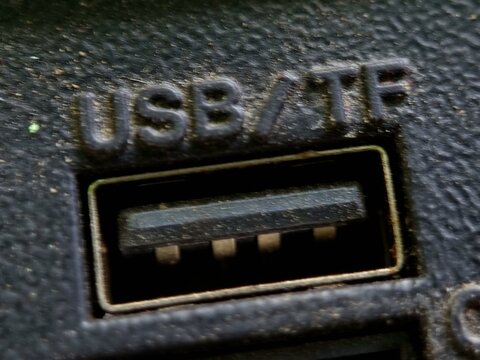 Macro close-up of a very dirty and dusty standard female USB Type-A port on an old device, with raised text USB  TF above it.
