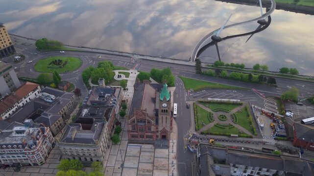 Aerial view of the historic Guildhall and the modern Peace Bridge spanning the River Foyle in Londonderry, United Kingdom.