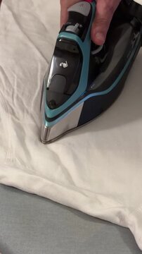 Ironing a shirt on a flat surface with a steam iron in a home setting