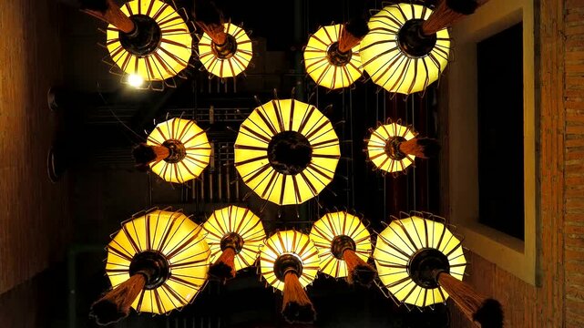 Low-angle under group of ancient Chinese lanterns with warm light hanging in darkness. Interior design concept