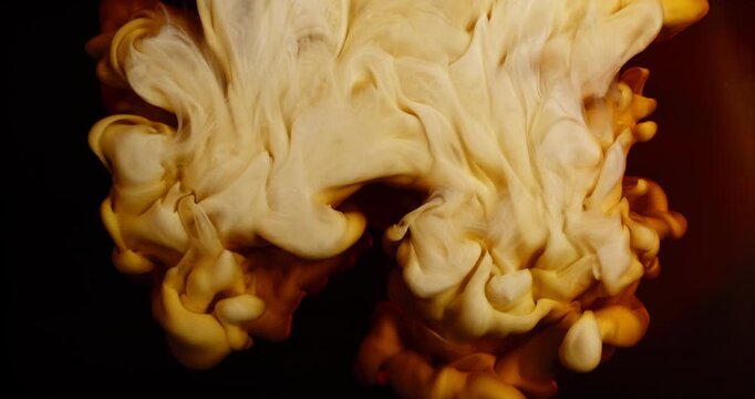 Extreme super slow motion of milk swirling and mixing into coffee, creating smooth creamy clouds and fluid abstract shapes in a dark liquid background. Speed ramp effect.
