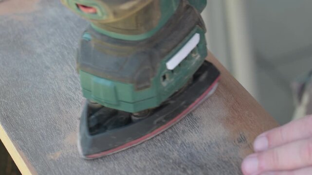 Old varnish removal from wood surface using sanding machine in outdoor space