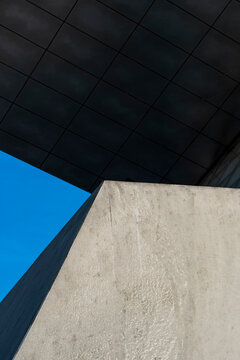 Concrete wall and ceiling frame triangular blue sky in minimal architecture where geometric planes and strong shadows turn the corner into an abstract detail