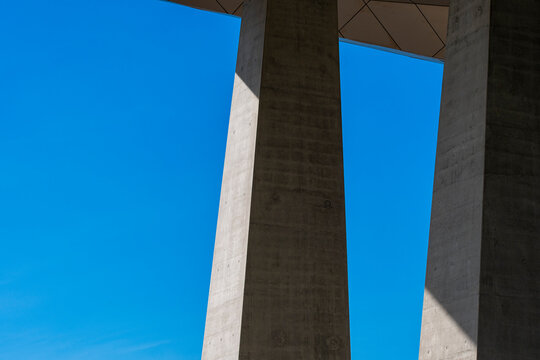 Concrete columns and shadows frame blue sky in abstract brutalist architecture where geometric structure creates strong negative space between vertical forms