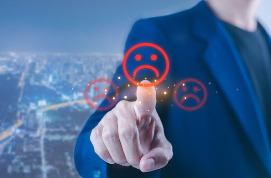 Customer dissatisfaction concept showing a professional touching a sad face icon on a digital interface, representing negative feedback poor service unhappy customers reviews, and business reputation.