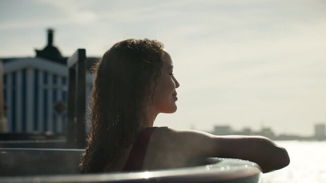 Woman relaxing in outdoor hot tub with steam and spa wellness view