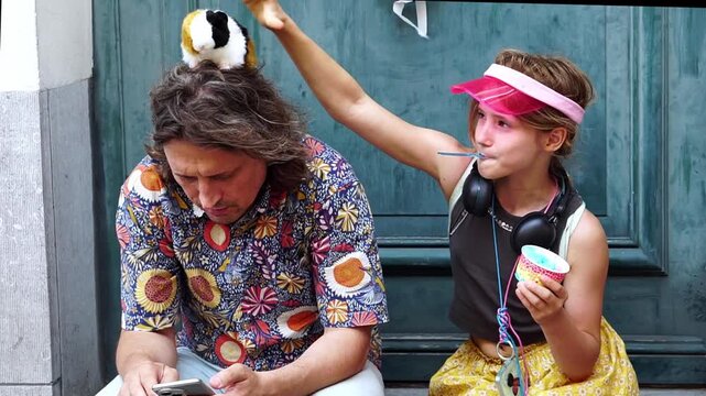 Girl eating ice cream while balancing a plush toy above an adult