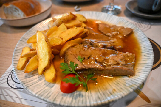 Veal baked under sač served with roasted potatoes. Traditional dish of tender roasted veal with potatoes on a plate.