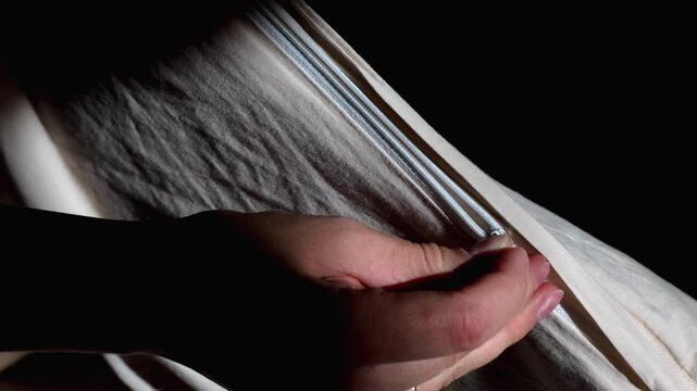 Close up of woman hands unzipping a hidden zipper on a beige duvet cover.
