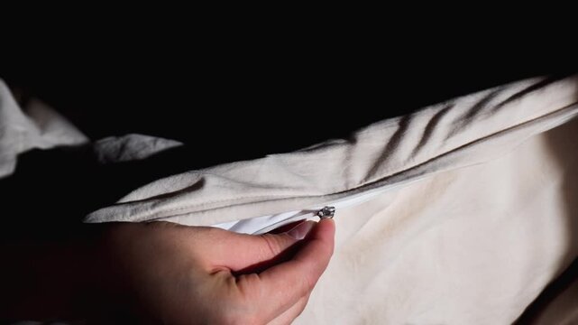 Close up of woman hands fastening a hidden zipper on a beige duvet cover.