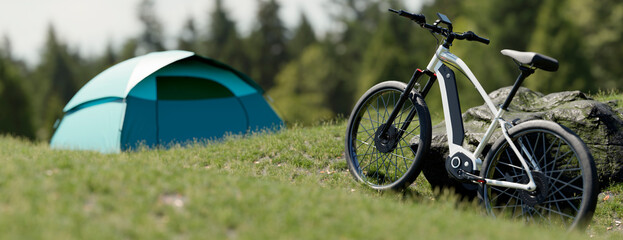 Electric bicycle parked next to a tent in a grassy field with trees in the background