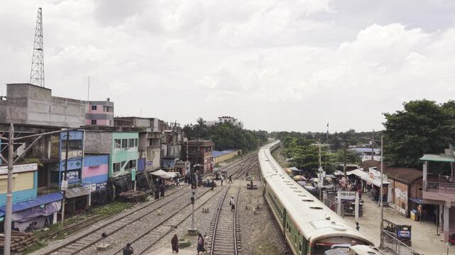 Poradah Junction, Kushtia, Bangladesh, 12 August 2026: A passenger train arrives at Poradah Junction railway station, approaching the platforms along the railway tracks, captured by an aerial drone.
