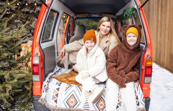 Family enjoying winter outdoors, sitting in a cozy van with warm blankets, surrounded by snow and festive decorations, capturing joyful moments of togetherness and warmth